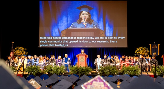 Audience listens to student speaker at 2026 Drexel Dornsife commencement 
